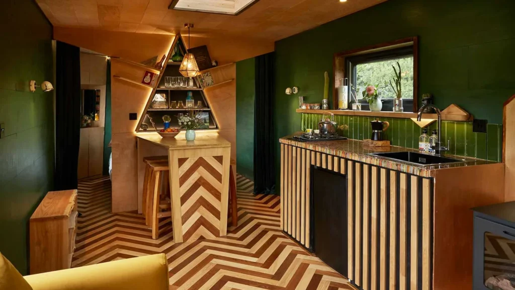 Stylish eco-cabin interior with chevron wooden floors, compact kitchen, and dining bar in Sussex