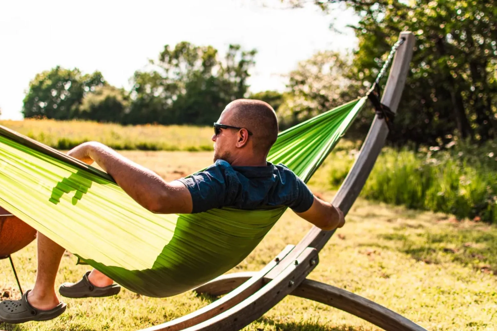 Guest relaxing in a hammock in the sunshine on the private meadow at the Vacationist eco-cabin
