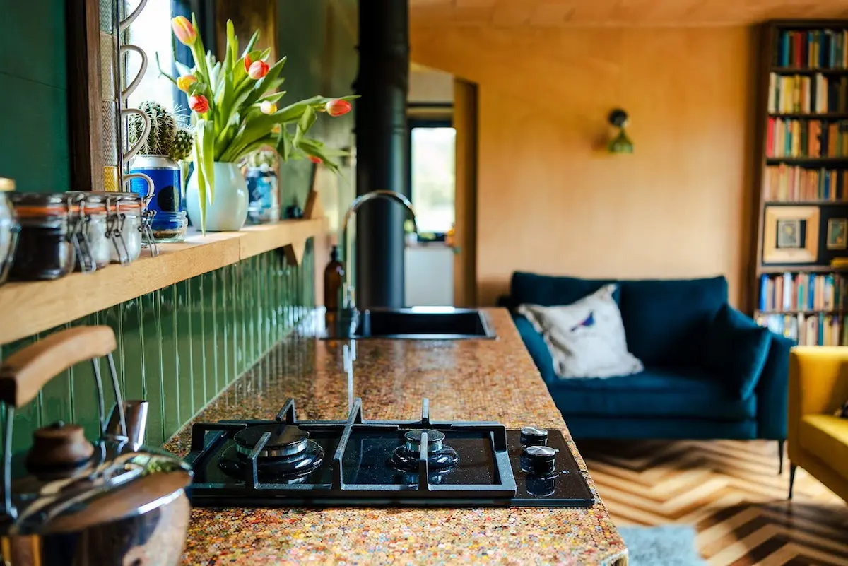 Stylish off-grid cabin kitchen and lounge with wood interiors, bookshelves and a cosy sofa