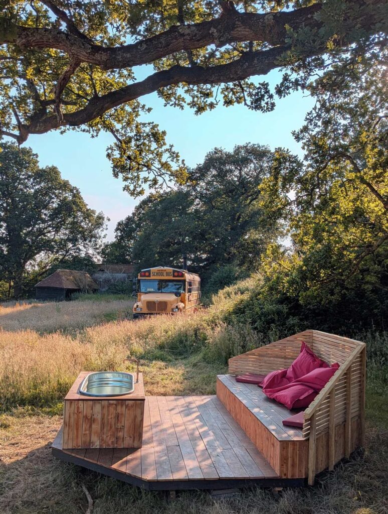 Private wood-fired hot tub beside Skoolie Stays converted American school bus in West Sussex